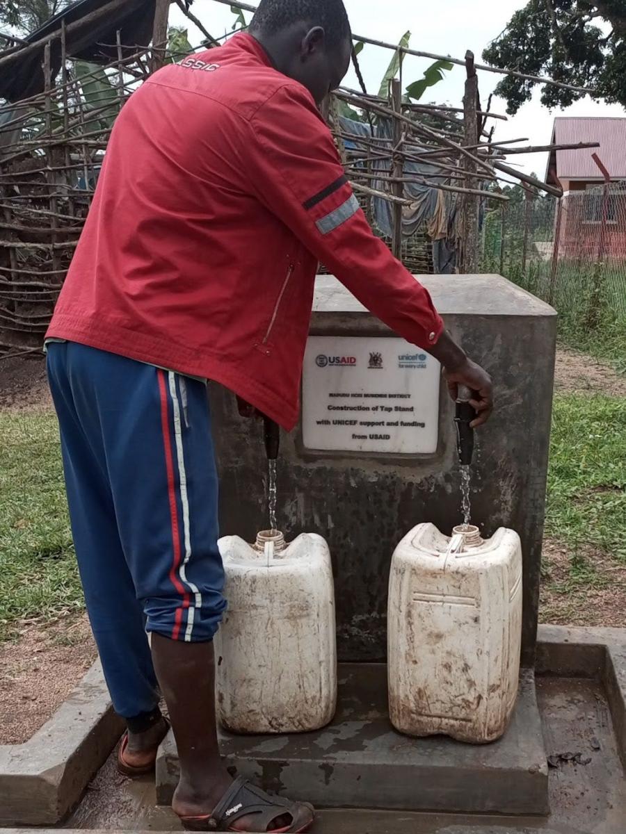 Man collecting clean water from a station at a health centre in Uganda