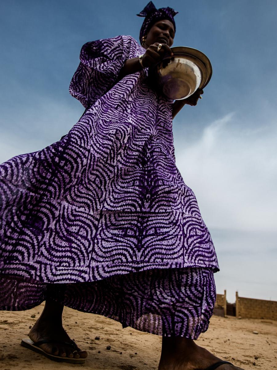 A woman in a purple dress that billows behind her as the wind blows.