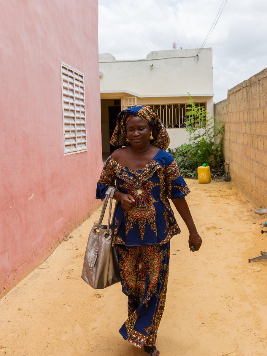 A woman carrying a large purse walks down an alley.