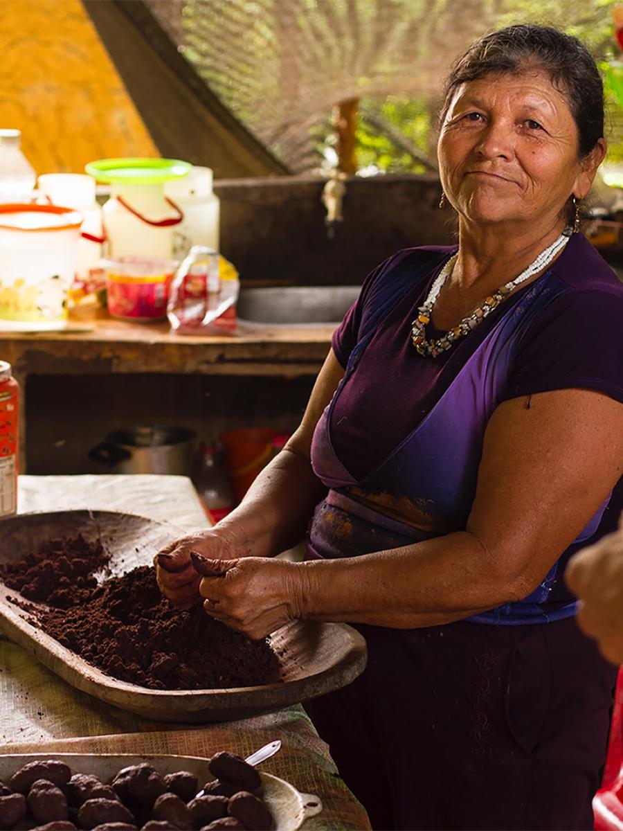 Woman sitting by a table preparing chocolate.