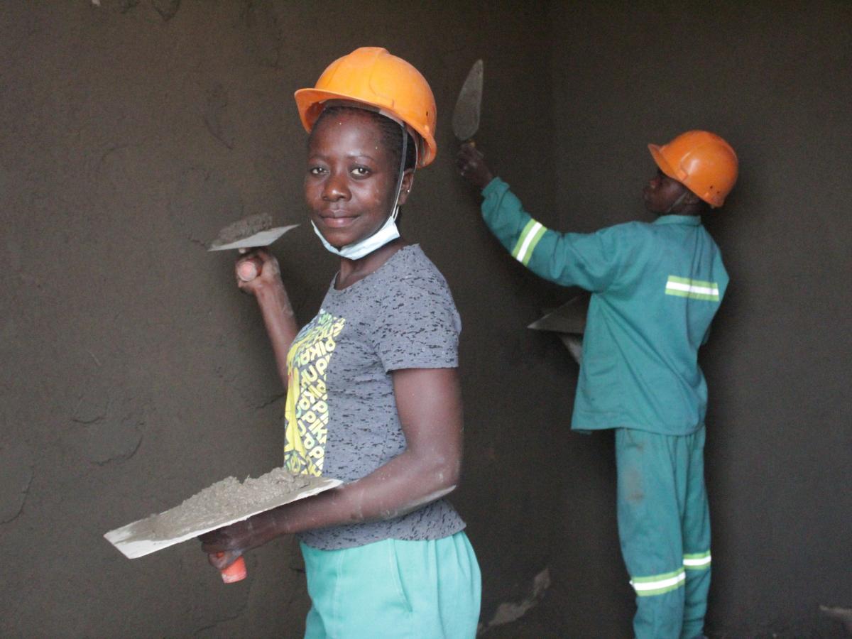 An adolescent mother putting concrete on a wall.