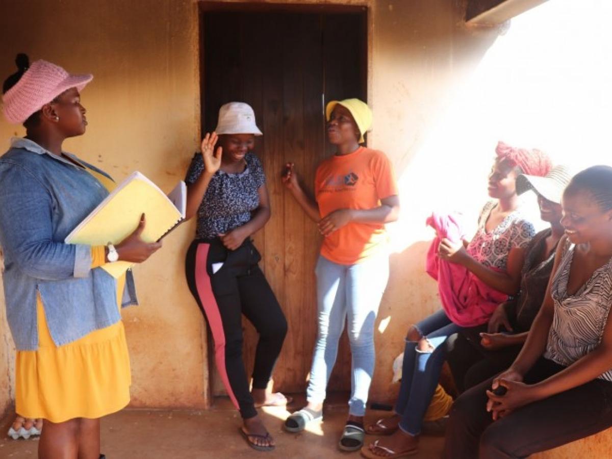 Gcinile (in the white hat) meets with the other young women she runs a chicken laying business with and their Business Mentor (carrying a booklet). Gcinile is a champion for HIV prevention in her community.