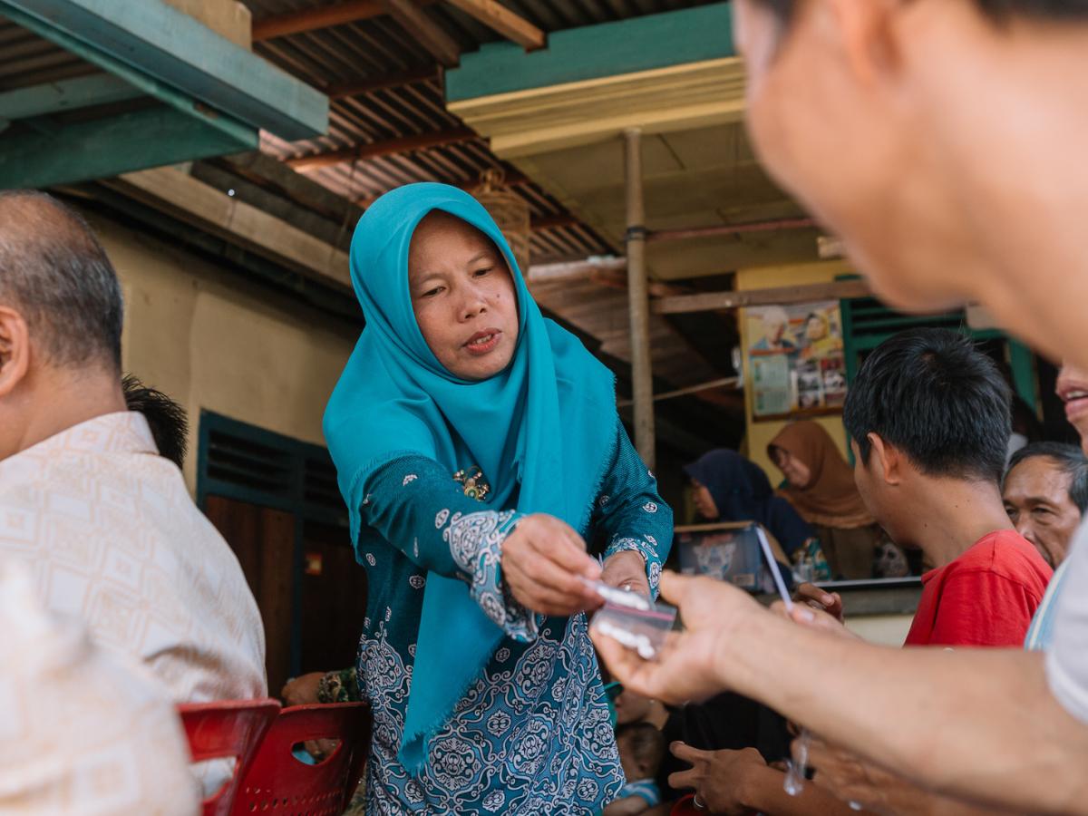 A health volunteer distributes medicines during mass drug administration for eradication of Lymphatic Filariasis in Gunung Gajah, Lahat, South Sumatra.