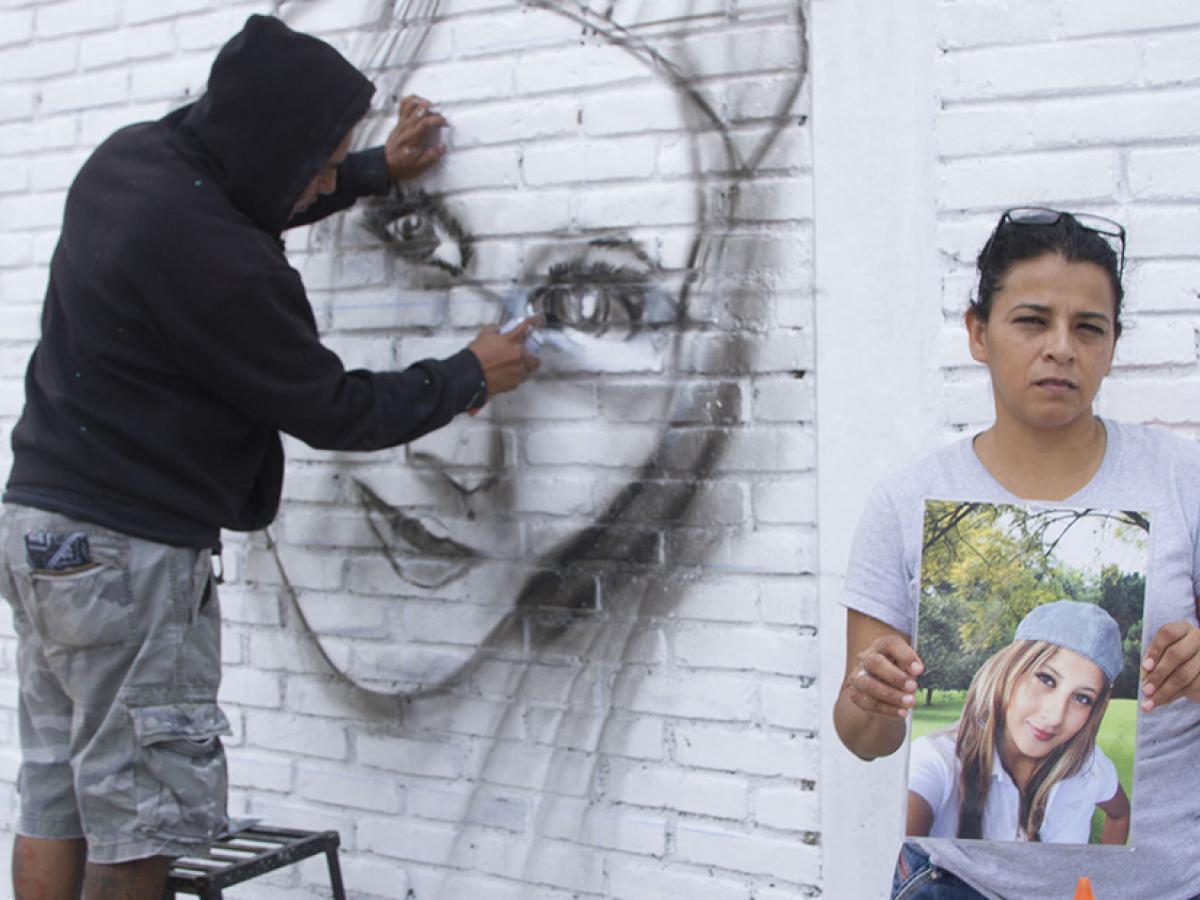 Mural painting of a disappeared woman with her mother showing her picture.