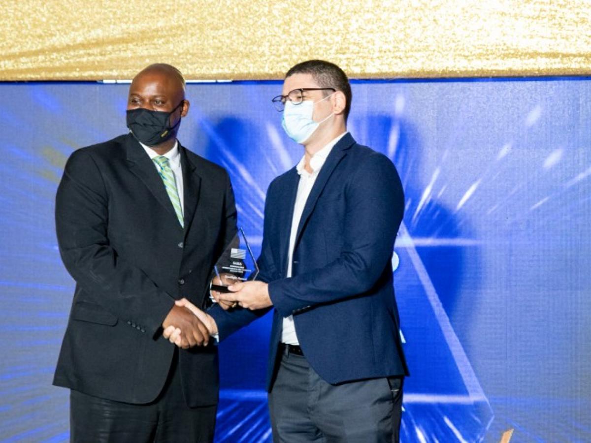 Jason Fraser (l), USAID Country Representative, presents The Spotlight Award to Dr. Geoffrey Barrow (r), Director Health Connect Jamaica, during the 2021 USAID Stakeholder Appreciation & Recognition Awards.