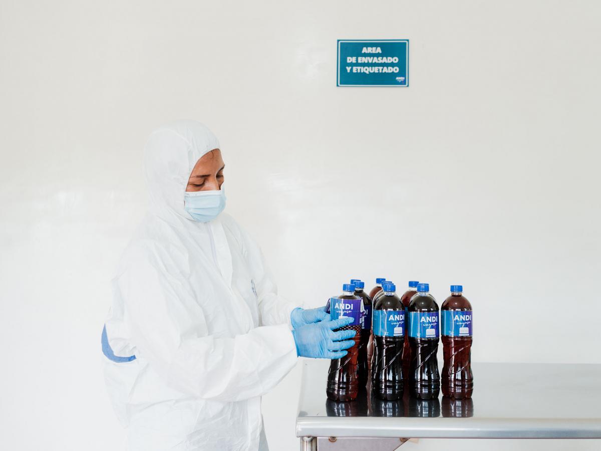 A woman in a production facility with several bottles of Andi Wayusa