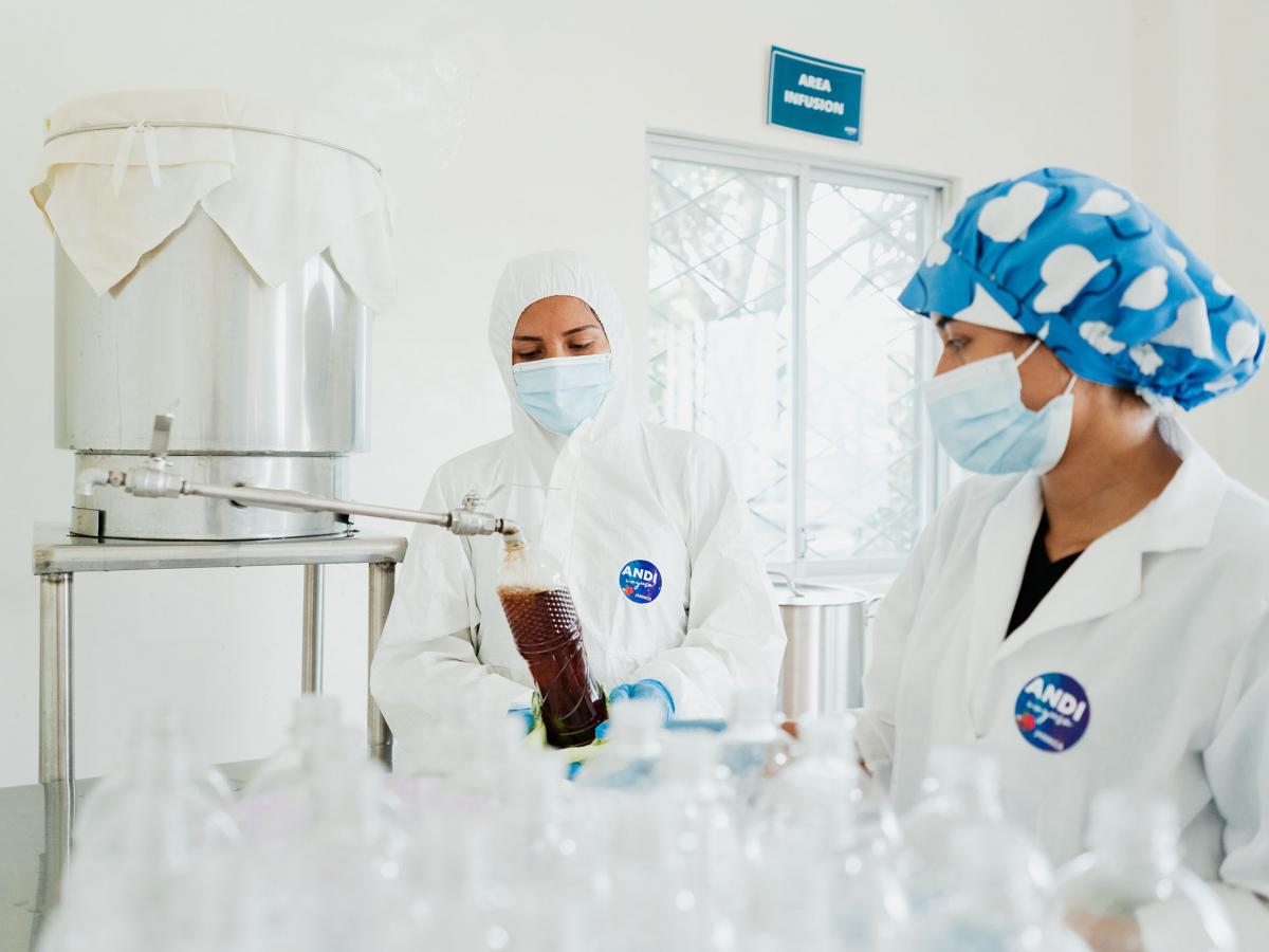 Two women in the production facility filling a bottle with the energizing beverage
