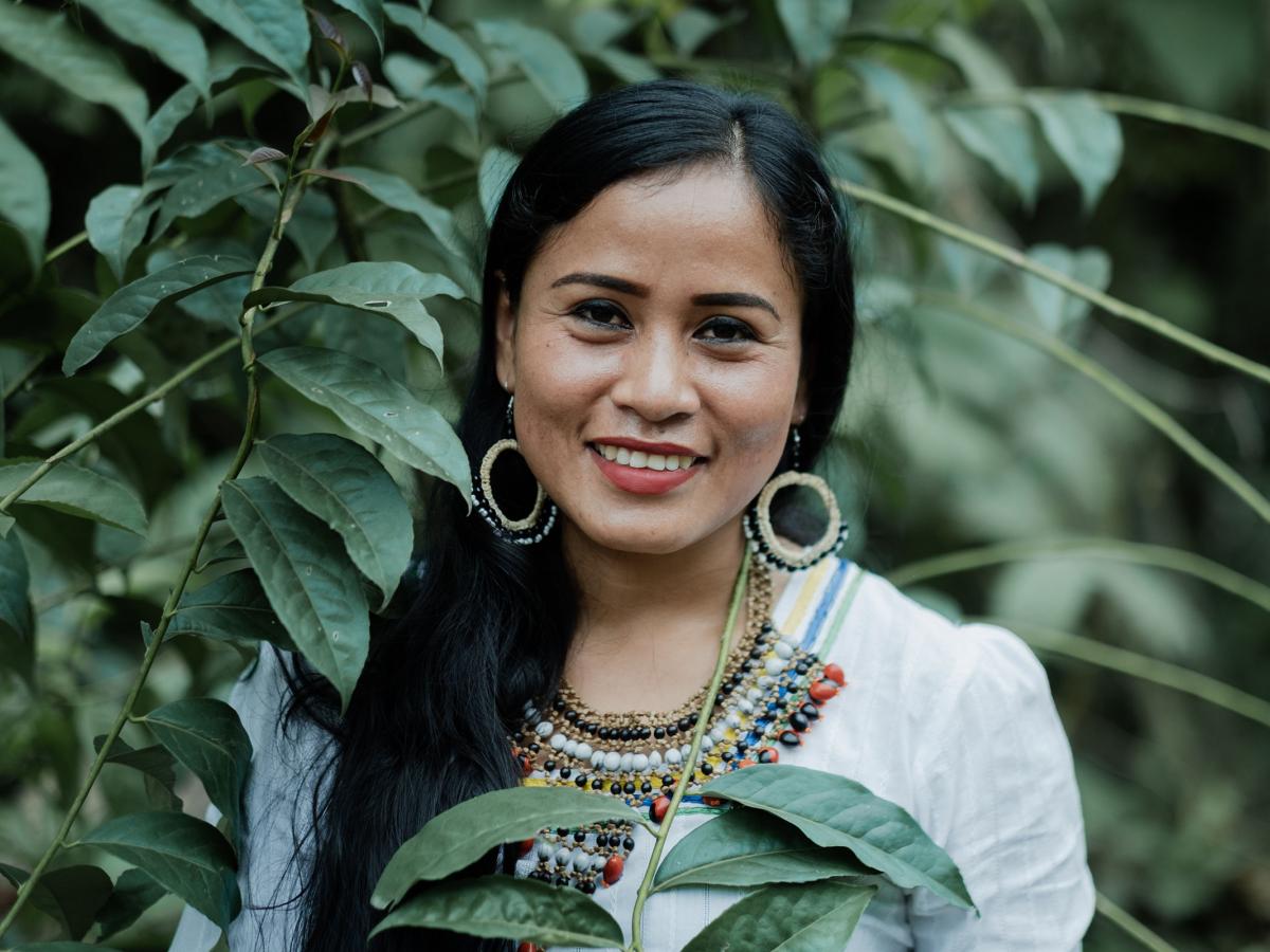 An indigenous woman surrounded by plants and smiling