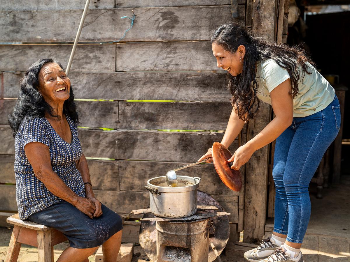 Young woman and and old woman cooking outside in a pot in the Amazon rainforest