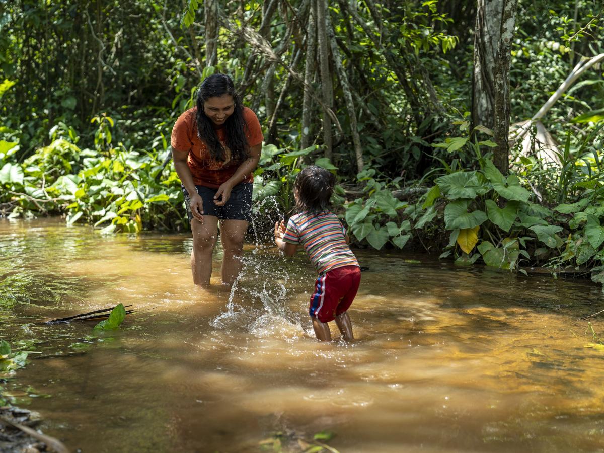 Young woman playing with a child in the river in the Amazon rainforest