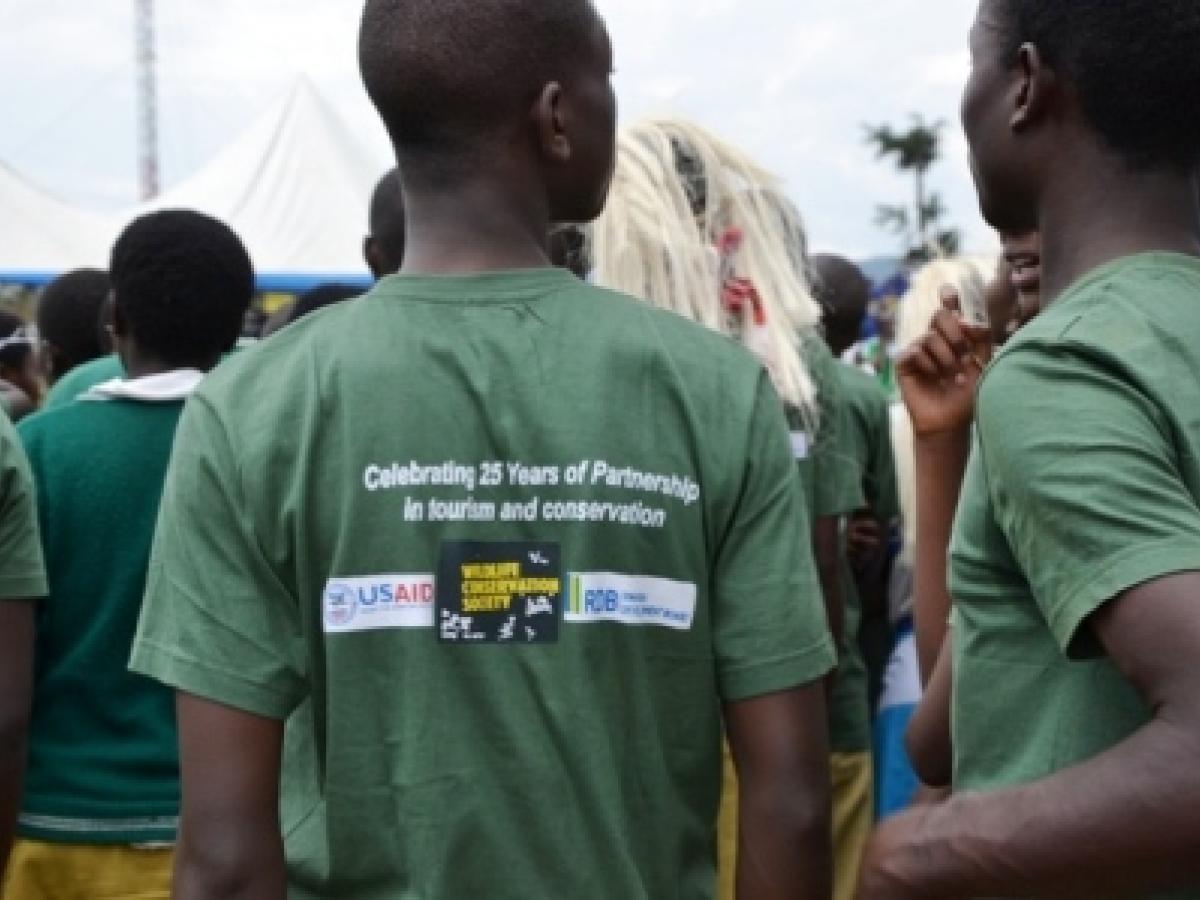 two Nuyngwe staff seen from the back, with the USAID project name on their shirts