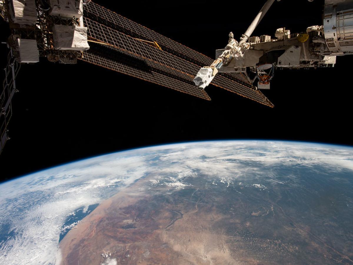 Photo of a satellite in space with the earth behind it (Photo Credit: NASA)