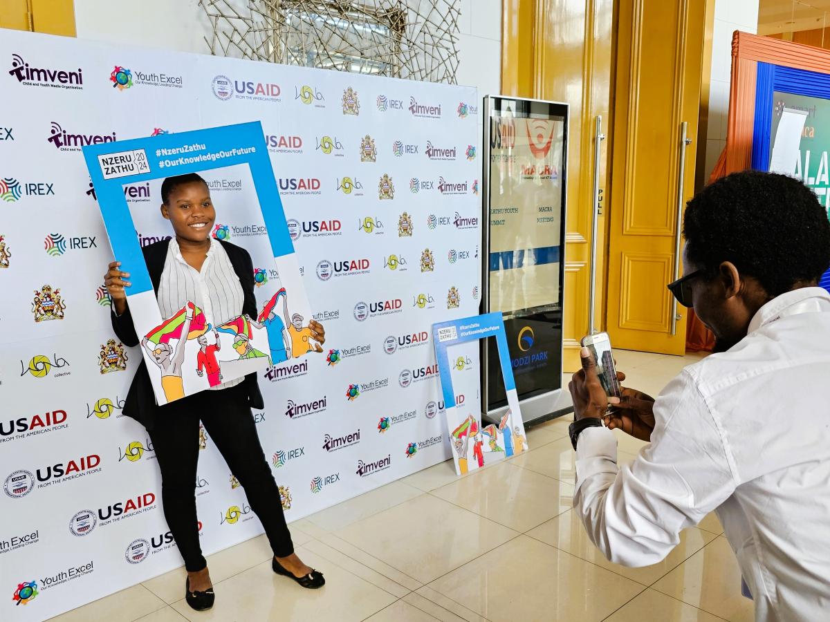 One of the participants in the Nzeru Zathu "Our Knowledge" Youth Summit poses for a photo in the open gallery outside the event hall. Photo: Oris Chimenya/USAID