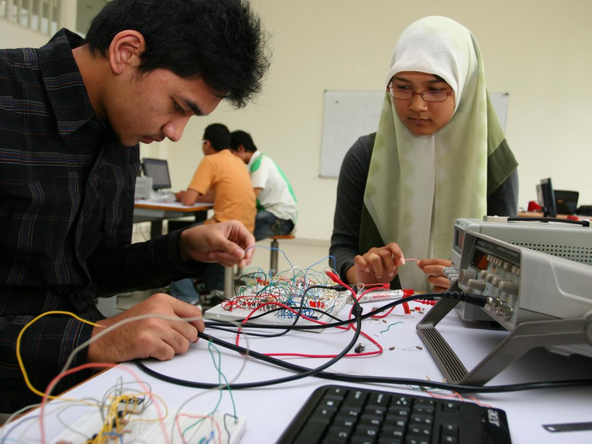 Dua mahasiswa sedang mempelajari riset terapan dan keahlian teknologi