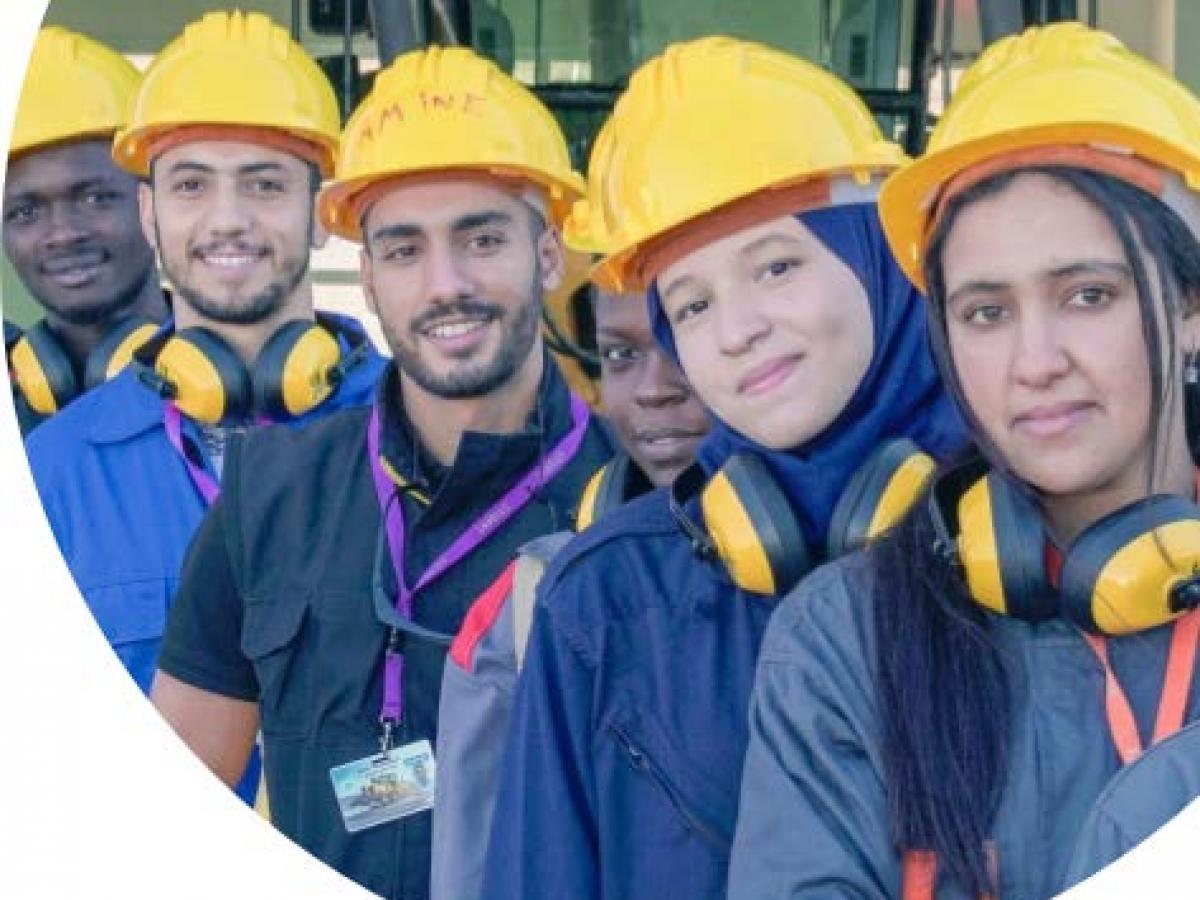 Young Moroccan and African trainees posing in a line with hard hats 