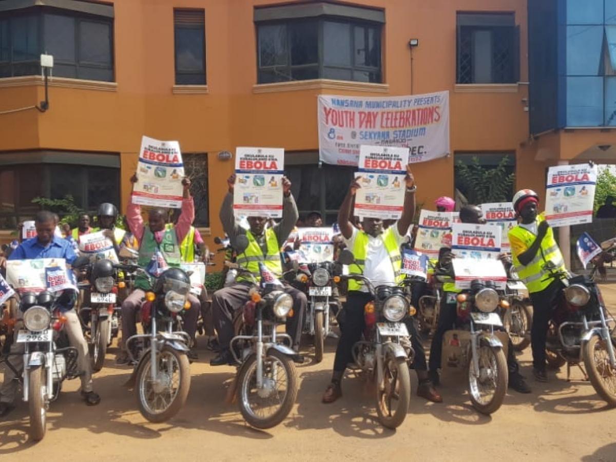 Group of motorcyclists parked in front of a building hold up fliers.