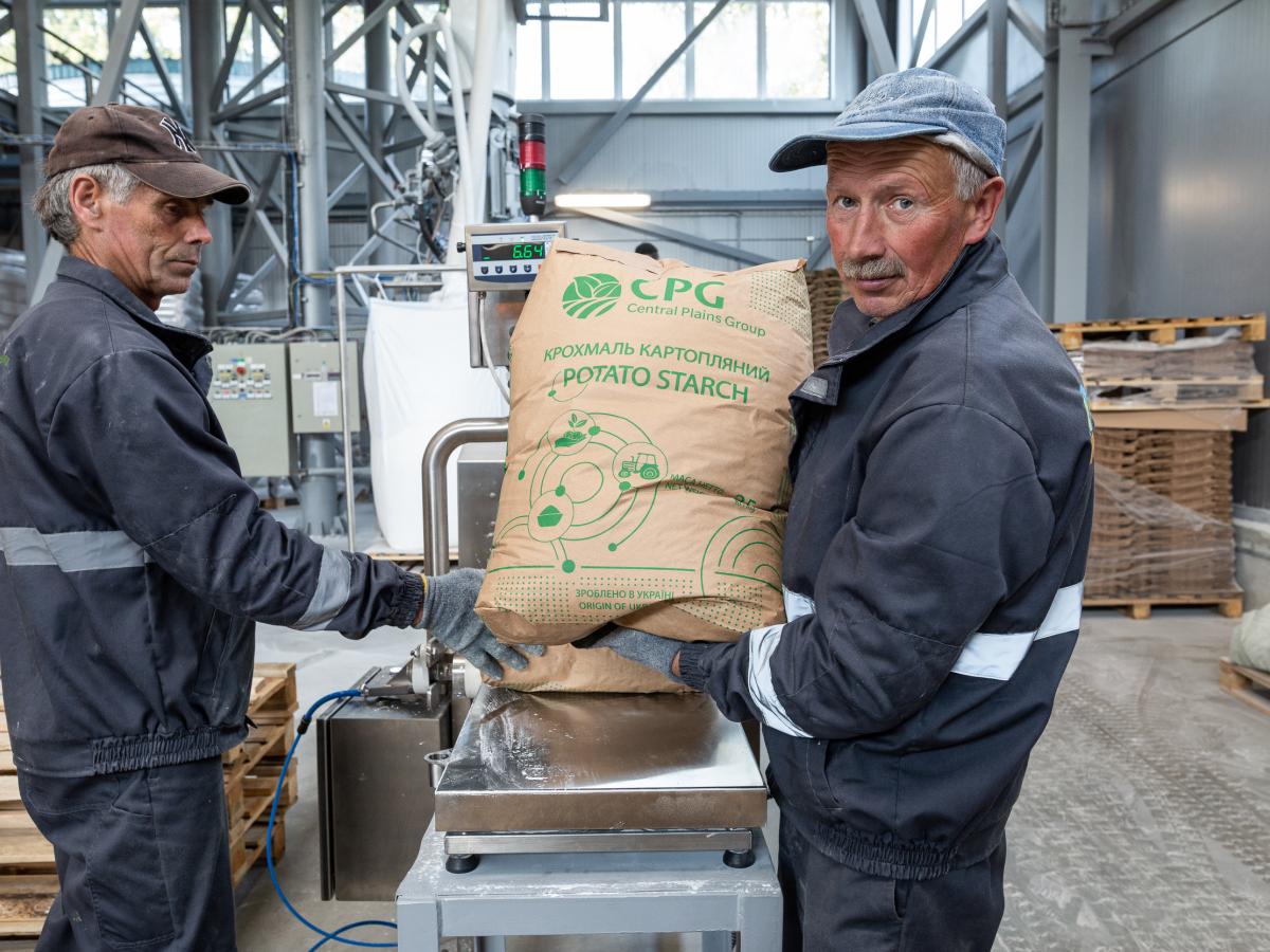 Two employees removing sacks of potato starch from a factory production line.