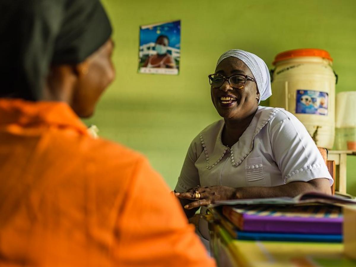 Adama sits at her desk with a patient at the Tamale Reproductive and Child Health Center in northern Ghana.