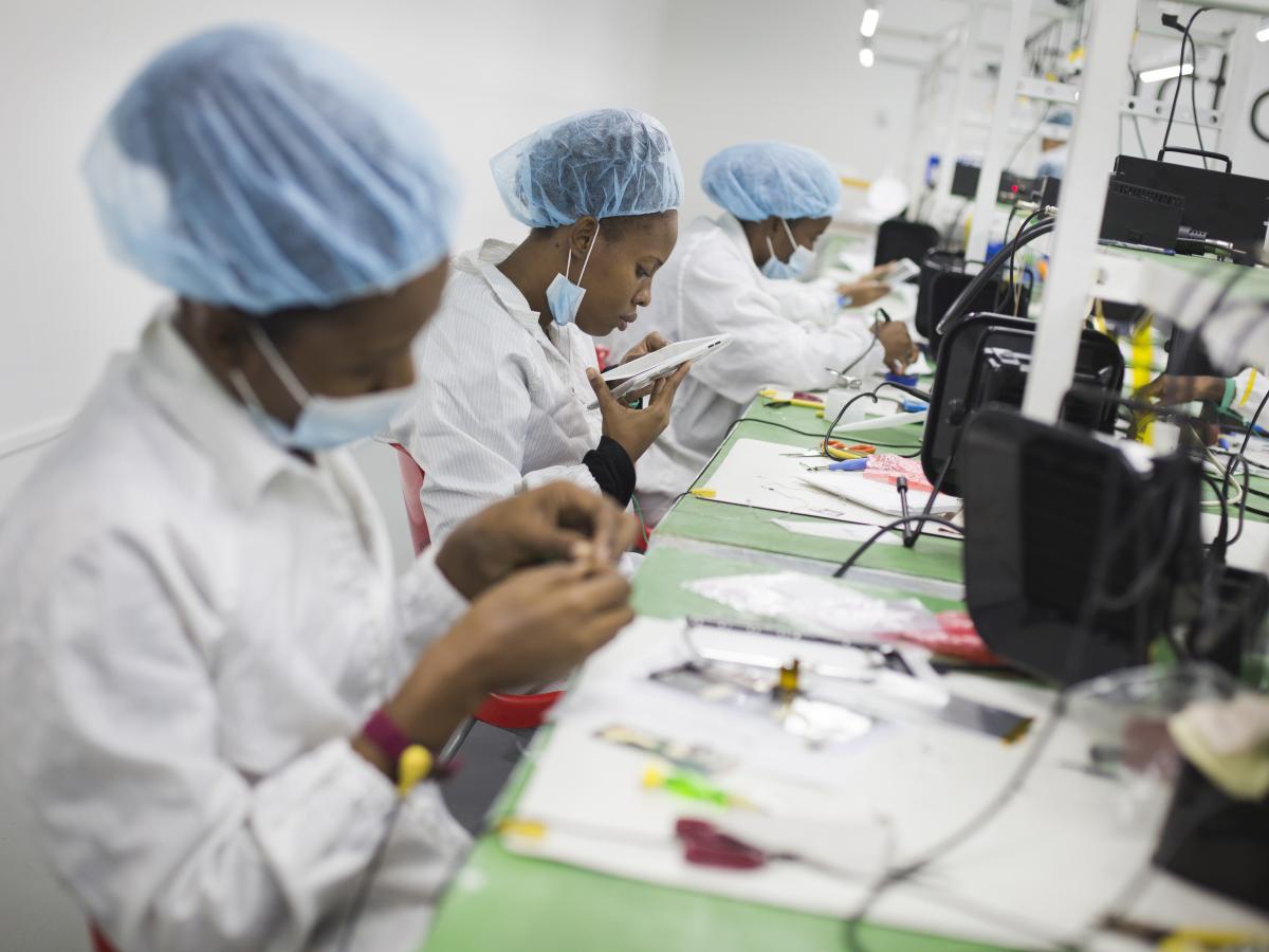 Three women work to build tablets in a factory.