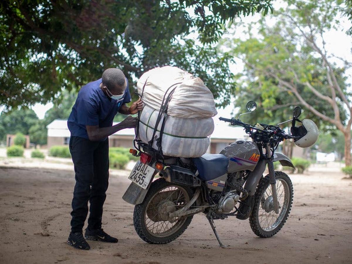 Collins Ngosa loads bed nets onto his motorbike to take to a distribution site.