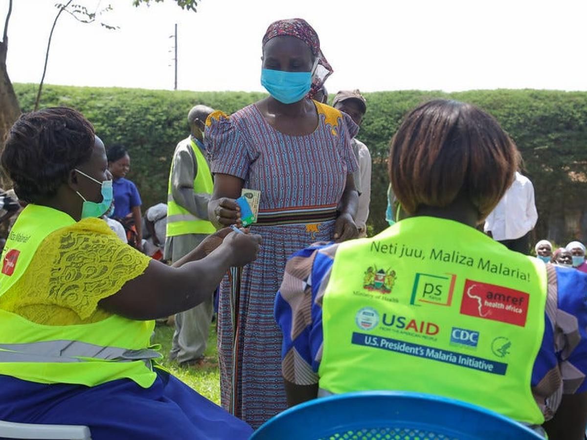 A woman provides identification to the USAID workers helping with the Mosquito net distribution campaign in Kenya. 