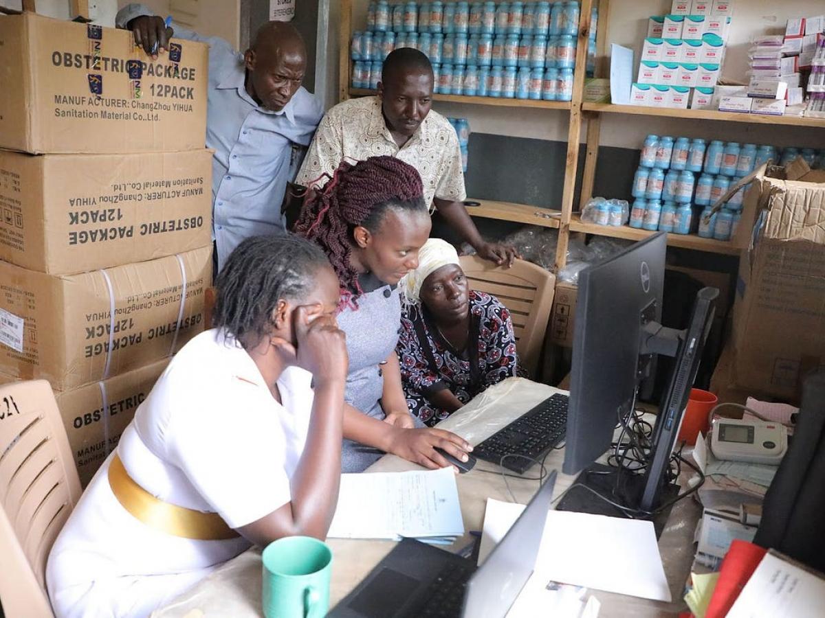 Health workers gather around a computer.