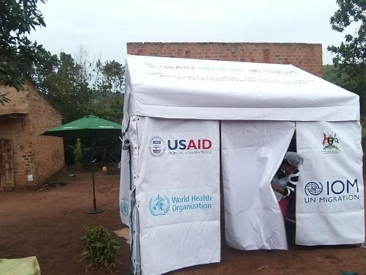 A medical personnel standing outside of an isolation medical tent as a person exits from the tent.. 