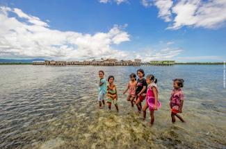 Photo: A group of Indonesian children collect shellfish from the shallow waters surrounding their seaside village.