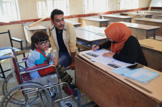 Ramez*, accompanied by his father, Abdulrahman*, receives a USAID-funded wheelchair at Habil Al Sabha Primary School, in Habil Jabr District, Lahj Governorate. 