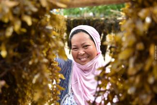 A woman smiles between patches of hanging seagrass