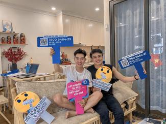 Two individuals pose with signs that are highlighting an HIV/COVID-19 hotline during a promotional session livestreamed on Blued, a gay dating app, where they provided information on COVID-19, COVID-19 and HIV prevention tips.