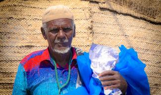 Image of Ethiopian man holding mosquito bed net