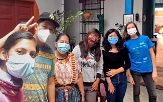 A people wearing medical face masks stand side by side to pose for a photo.