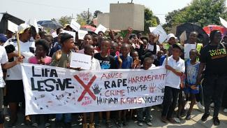 A group of Southern Africans carry signs and a banner protesting human rights abuses