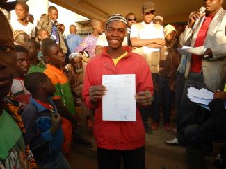 A young boy in the Sahel region of Burkina Faso receives his birth certificate, a crucial document that will enable him to access public services, travel to school and markets, and pursue future employment opportunities.