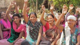 a group of women raising their hands at an outdoor community meeting