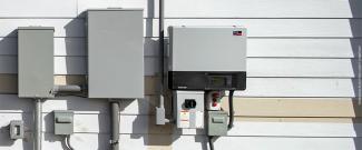 Photo of an electric power inverter and electrical boxes on the side of a residential building