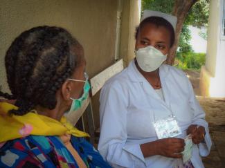 A TB healthcare worker checks up on a TB patient.