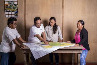 Four people gathered around a table looking at a forest concession map