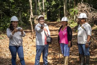 Four people in the Amazon rainforest holding a drone 