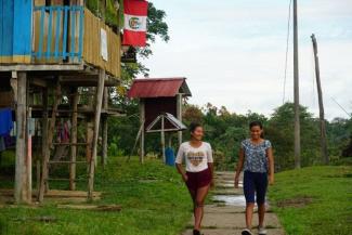 Indigenous women walking next to their houses
