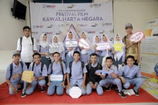 Students in Ternate, North Maluku pose for a photo in front of the banner for the BPK Film Festival, supported by USAID on March 3, 2017.