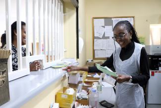 Anna Naukushu dispensing medication to a client at the pharmacy.
