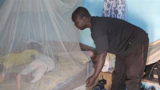 : Mr Mahamat installing a Long Lasting Mosquito Net for his children before bedtime following the guidance of the CHW- Guider, North Cameroon. Photo credit: Christelle Ngueajio, DOC USAID.