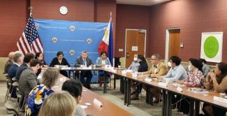 U.S. and Philippine government officials and members of the diplomatic community sitting in a room around tables.