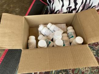 A box of life-saving HIV treatment in bottles. USAID provides life-saving HIV treatment in accessible locations, such as through community-based differentiated service delivery models, making it easier for people living with HIV to pick-up their medications. 