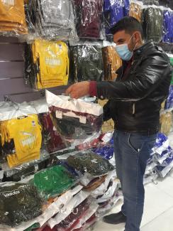 Khalaf Yousif selects different pieces to stock his new clothing shop in Khanki Camp in Duhok