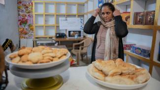Nadia, 43, proudly sells homemade Iraqi pastries in her new shop that she opened with support from USAID.