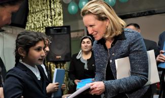 USAID Deputy Administrator Isobel Coleman hands over large font books at Hisor Specialized School in Tajikistan, February 2023