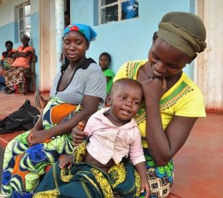 A mother and her child wait outside a USAID-supported clinic in Zambia.